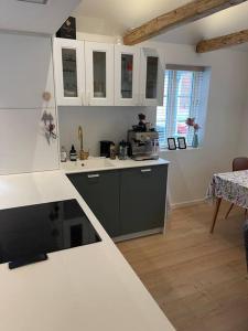 cocina con armarios blancos y encimera en Hyggeligt lille byhus lige mellem havnen og bytorv, en Ringkøbing