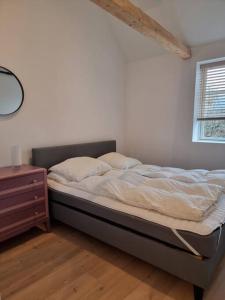 1 cama no hecha en un dormitorio con ventana en Hyggeligt lille byhus lige mellem havnen og bytorv, en Ringkøbing