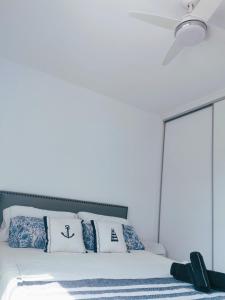 a bed with blue and white pillows and a ceiling fan at Apartamento Canyelles playa in Roses