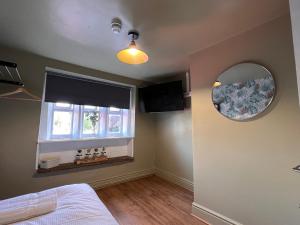 een slaapkamer met een spiegel en een raam bij The Ring O'Bells in Halifax