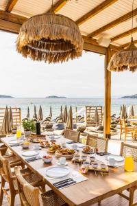 uma longa mesa de madeira com comida na praia em Skiathos Thalassa Cape Hotel, Philian Hotels and Resorts em Megali Ammos