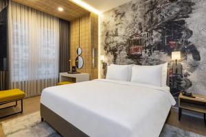 Days Hotel by Wyndham Istanbul Esenyurt في إسطنبول: غرفة نوم بسرير ابيض كبير وجدار جداري