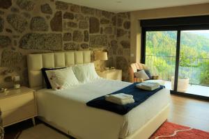 - une chambre avec un lit et un mur en pierre dans l'établissement Vila de Campos - Gerês, à Vieira do Minho