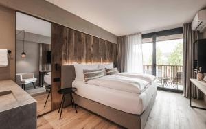 a bedroom with a large bed and a balcony at Hotel Löwenhof in Bressanone