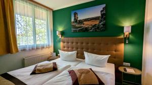 een slaapkamer met een groot bed met een groene muur bij Acron-Hotel Quedlinburg in Quedlinburg