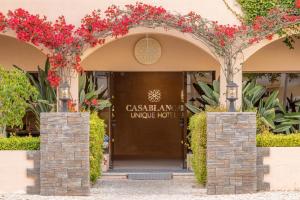 uma entrada para um hotel com flores vermelhas em Casablanca Unique Hotel em Monte Gordo