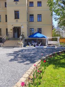 um edifício com um guarda-chuva azul e algumas flores em Willa Pod Gwiazdami & SPA em Kudowa-Zdrój