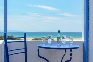 - une table avec deux bouteilles et des verres sur un balcon dans l'établissement Psili Ammos Studios, à Plage d'Aliko