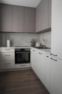 uma cozinha com armários brancos e um forno preto em Luxuria Modern Apartments - Self Check-in em Šiauliai