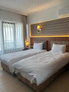 um quarto de hotel com duas camas com lençóis brancos em Hotel Stella em Kusadası