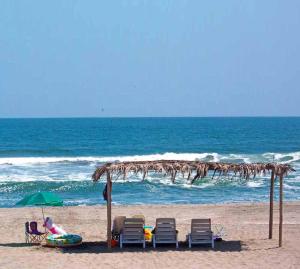 eine Frau auf einem Stuhl unter einem Sonnenschirm am Strand in der Unterkunft Topara Hotel Boutique in San Vicente de Cañete