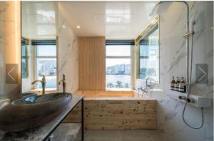 baño con lavabo de madera y ventana grande en De Homme Hotel, en Busan