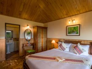 een slaapkamer met een bed, een wastafel en een spiegel bij Willow Hill by Nature Resorts in Ooty