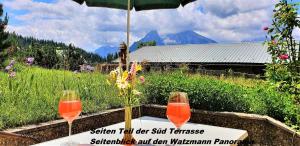 zwei Weingläser auf einem Tisch mit einem Regenschirm in der Unterkunft Ferienhaus hoch oben mit Alpen Panorama Königssee- Nichtraucherdomizil in Berchtesgaden