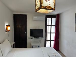 a bedroom with a bed and a tv and a window at Pousada Beijos y Abraços in Natal