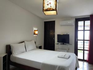 a bedroom with a white bed and a television at Pousada Beijos y Abraços in Natal