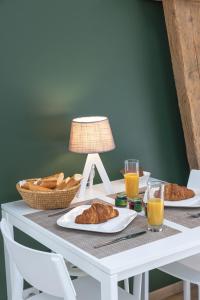 uma mesa com croissants e cestas de pão e sumo de laranja em Gîte Le Haut des Vannes em Neufchâteau