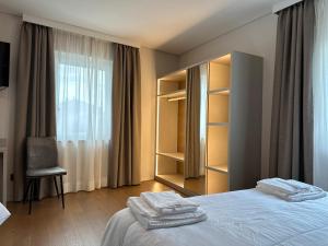 een slaapkamer met een bed, een stoel en een raam bij Hotel Riviera in Magnano in Riviera