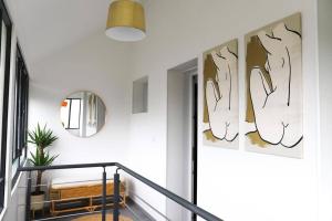 a hallway with white walls and a staircase with art on the wall at Très Belle MAISON à Rennes St Jacques in Saint-Jacques-de-la-Lande