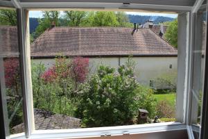 an open window with a view of a garden at A CÔTE in Môtiers