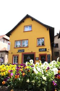 a yellow house with flowers in front of it at A CÔTE in Môtiers