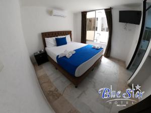 una camera da letto con un letto con lenzuola blu e una finestra di Blue Star Hotel a Melgar