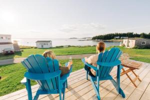 twee vrouwen zittend in stoelen op een terras kijkend naar de oceaan bij Seahorse Cottage in Indian Harbour