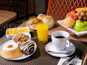 - une table avec des assiettes de produits pour le petit-déjeuner et une tasse de café dans l'établissement ibis Ponta Grossa, à Ponta Grossa