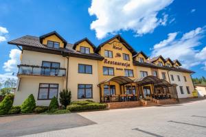 ein großes gelbes Gebäude mit einem Dach in der Unterkunft Hotel Szelców in Lesko