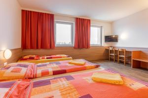 2 camas en una habitación de hotel con cortinas rojas en OEKOTEL Treffpunkt Föhrenhain, en Föhrenhain