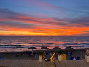 puesta de sol en la playa con sillas y sombrillas en Romantic Palace Beach Apartments, en Agios Gordios