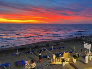 un grupo de personas de pie en una playa al atardecer en Romantic Palace Beach Apartments, en Agios Gordios