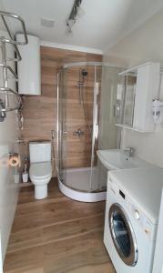 a bathroom with a shower toilet and a washing machine at Апартаменти - Історія з вікна in Kamianets-Podilskyi