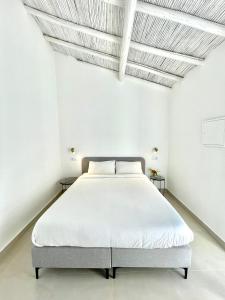 uma cama num quarto branco com paredes brancas em Casa XS em Alvor