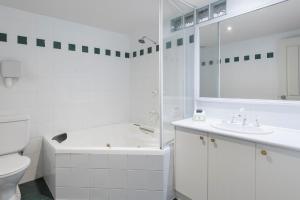 a white bathroom with a sink and a tub and a toilet at Elizabethan Lodge in Melbourne