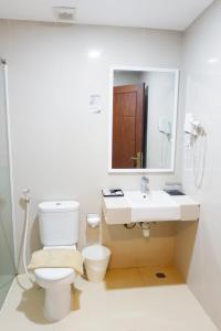 a bathroom with a toilet and a sink and a mirror at Vega Prime Hotel & Convention in Sorong