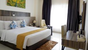 a hotel room with a large bed and a desk at Vega Prime Hotel & Convention in Sorong