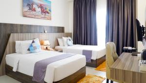 a hotel room with two beds and a desk at Vega Prime Hotel & Convention in Sorong