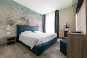 - une chambre avec un lit bleu et un mur en pierre dans l'établissement Hotel Colombo, à Lido di Jesolo