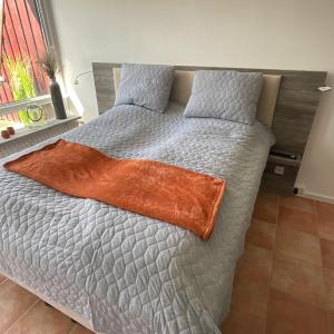 een bed met een oranje deken erop bij Ferienwohnung 1 Zimmer App Ankerplatz 43 im Olympiazentrum in Kiel