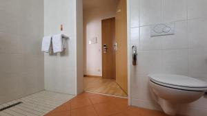 a bathroom with a toilet and a door with towels at Hotel Kindler 2,0 Self-Check-In in Leoben