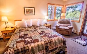 a bedroom with a bed and a chair and windows at McGregor Mountain Lodge in Estes Park