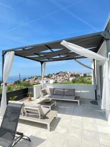 une terrasse avec un baldaquin noir, des chaises et un canapé dans l'établissement Villa Fortuna, à Podstrana