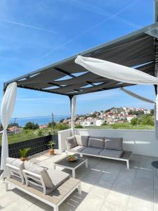 une terrasse avec un parasol blanc, un canapé et des chaises dans l'établissement Villa Fortuna, à Podstrana