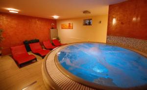 uma grande banheira num quarto com cadeiras vermelhas em Wellness Pension 7 em Harrachov