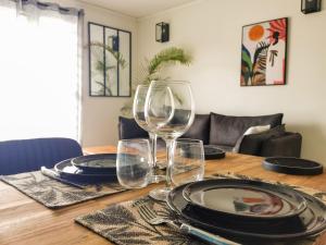 un tavolo in legno con bicchieri da vino e piatti di Le Théâtre du Vieux Foyal - Appartement 4 personnes à Fort-De- France a Fort-de-France