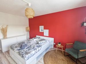 una camera da letto con una parete rossa, un letto e una sedia di Le Théâtre du Vieux Foyal - Appartement 4 personnes à Fort-De- France a Fort-de-France