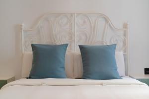 een wit bed met twee blauwe kussens erop bij Sabbia Suites La Armada in Arrecife