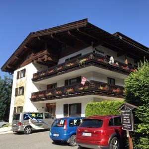 twee auto's geparkeerd voor een gebouw bij Pension Baranek - Baranek Resorts in Kaprun