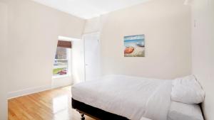 a white bedroom with a bed and a painting on the wall at Homeport Motel in Lunenburg